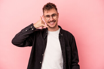 Young caucasian man isolated on pink background showing a mobile phone call gesture with fingers.