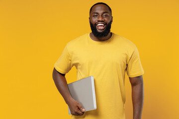 Young cheerful copywriter fun happy black man 20s wearing bright casual t-shirt hold use closed...