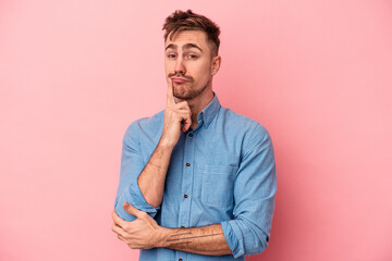 Young caucasian man isolated on pink background unhappy looking in camera with sarcastic expression.