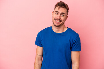 Young caucasian man isolated on pink background laughs and closes eyes, feels relaxed and happy.