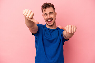 Young caucasian man isolated on pink background raising both thumbs up, smiling and confident.