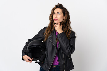 Young caucasian woman holding a motorcycle helmet having doubts while looking up