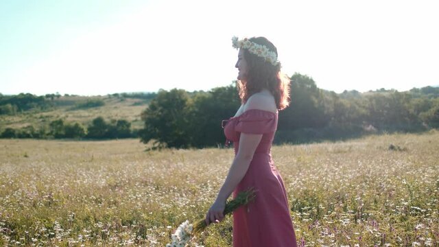 beautiful young woman in chamomile field in picturesque valley over sunset. young lady in red dress enjoy spring green nature, harmony concept. idea of self-care, healthy lifestyle, freedom