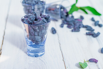 Dark blue honeysuckle berry in glass cups on a white wooden table