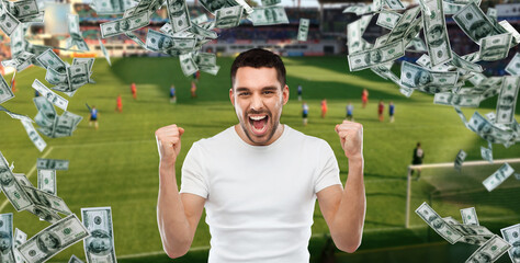 online betting, gambling and sport concept - happy man with raised hands and money rain over...