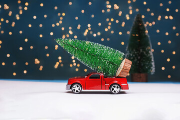 Red car on the background of the forest carries a Christmas tree