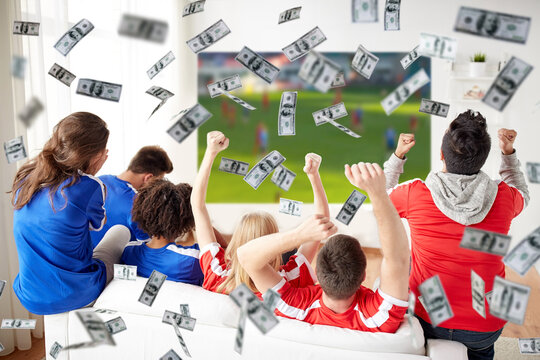 online betting, gambling and sport concept - happy friends or football fans watching soccer on tv and celebrating victory at home over money rain