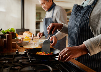 Happy multi-cultural elderly couple cooking healthy breakfast together in modern kitchen. 