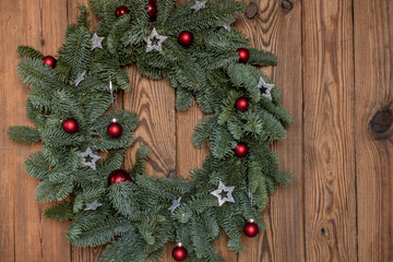 Simple eco-style Christmas wreath made from fresh needles nobilis, Danish pine. Decorated with red Christmas balls and silver stars. Copy space