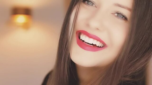 Holiday makeup look and beauty face portrait. Happy beautiful woman smiling, red lipstick make-up and pearly white teeth smile. High quality FullHD footage