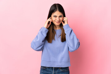 Young caucasian woman isolated on pink background frustrated and covering ears