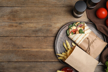 Delicious chicken shawarma and French fries served on wooden table, flat lay. Space for text