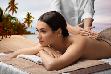 Obraz na płótnie Canvas wellness, beauty and relaxation concept - beautiful young woman lying and having back massage at spa over tropical beach background in french polynesia