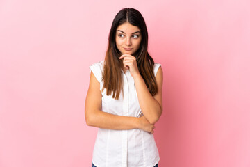 Young caucasian woman isolated on pink background having doubts and thinking