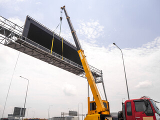 Construction site crane is lifting a led signboard for advertisement