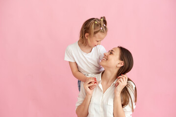 Lovely beautiful young mother and little daughter hug and look at each other. Photo in the studio. Copy space.