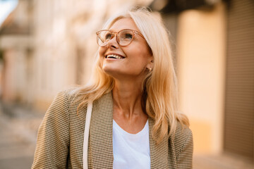 Mature white woman wearing eyeglasses smiling and looking upward
