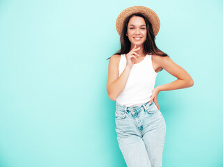 Young beautiful smiling female in trendy summer  clothes. carefree woman posing near blue wall in studio. Positive brunette model having fun. Cheerful and happy. In hat