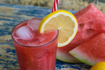 Summer drink watermelon and lemon smoothie in a glass glass with ice and a straw, sliced fruits. The concept of tasty and proper nutrition