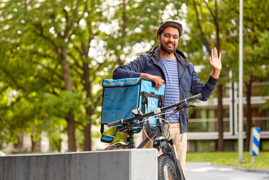 food shipping, profession and people concept - happy smiling delivery man with thermal insulated bag and bicycle on city street