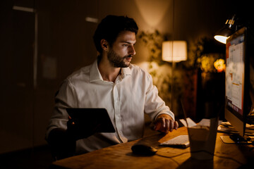 White bearded man working with tablet computer in evening