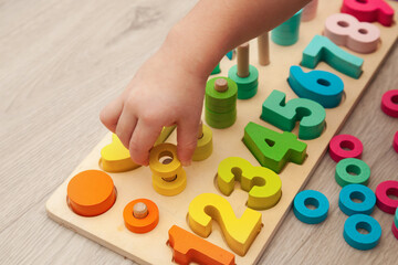 The child is playing with a colorful wooden educational toy. - obrazy, fototapety, plakaty