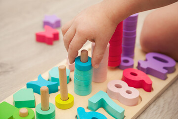 The child is playing with a colorful wooden educational toy.