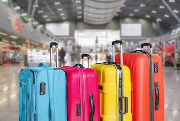 Modern stylish suitcases standing in empty airport hall, unrecognizable traveller's luggage