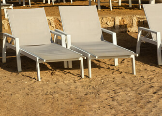 two light empty sun loungers on deserted beach in early morning. Rest and holiday concept, vacation background with copy space