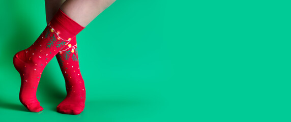 Feet of obscured child in Christmas socks standing against green background