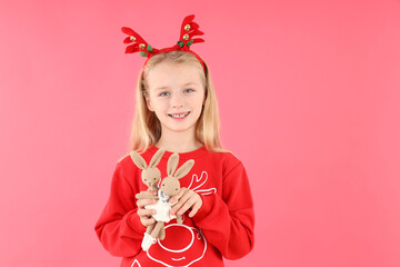 Little girl with toy rabbits on pink background
