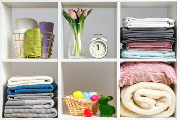 Organization of storage. Stacks of towels, sheets, bed linen, blankets and pillows on a white...