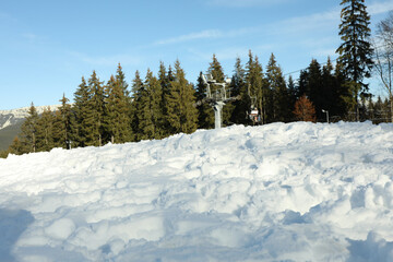 Fototapeta na wymiar Snow against ski lift, forest and blue sky