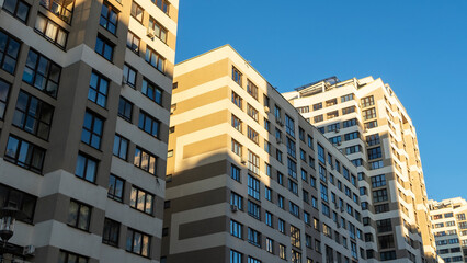 Cramped courtyard near high-rise buildings. A large apartment building in the background of a blue sky.