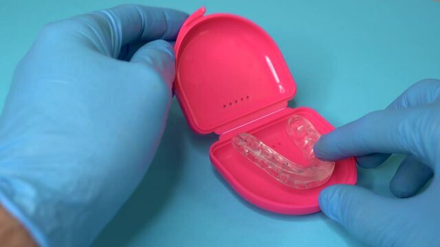 Doctor putting a dental retainer or dental splint from a pink boxset