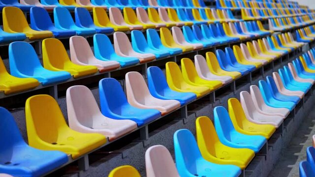 Multi-colored chairs in the stadium. Rows of empty plastic seats in the arena