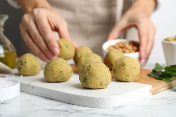 Woman making falafel balls at white marble table, closeup