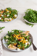 Plate of salad arugula leaves, canned corn, chicken, cucumber and feta cheese. Salad bowl, healthy food. Fresh salad