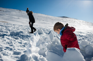 Un niño observa curioso la nieve mientras su madre pasea cerca