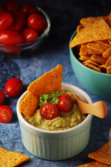 Homemade guacamole with corn chips and cherry tomatoes	