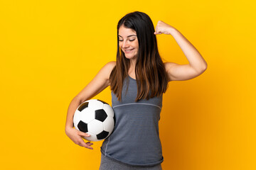 Young football player woman isolated on yellow background celebrating a victory