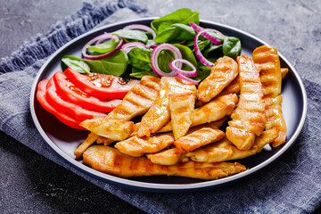 grilled chicken strips on a plate with vegetables
