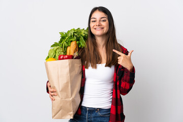 Young caucasian with vegetables isolated on white background giving a thumbs up gesture