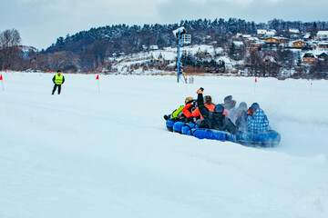 family ride down by snowing hill with snow tube
