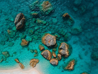 directly above woman in red swimsuit at the rock surrounded by the sea