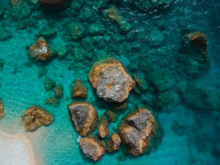 directly above woman in red swimsuit at the rock surrounded by the sea