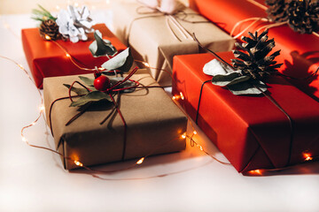 Red and brown gifts decorated with dried flowers and pine cones on a light background. Christmas...