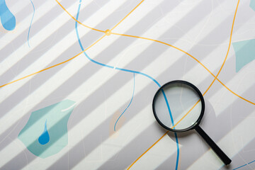 Magnifying glass on the background of city map, light through the blinds