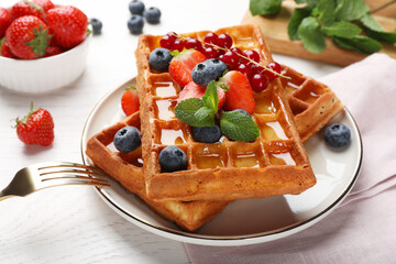 Delicious Belgian waffles with berries served on white wooden table