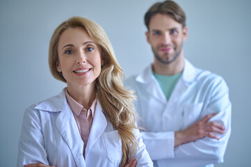 Woman in white coat looking at camera and colleague